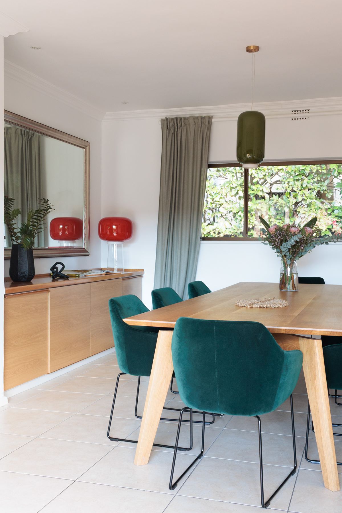 Dining table with green velvet chairs and a sideboard
